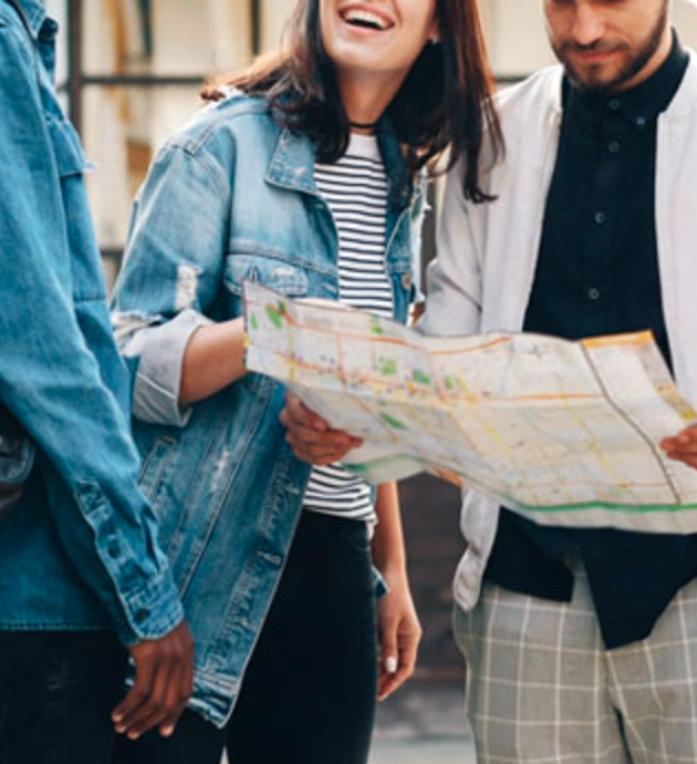 Three people standing together outdoors, looking at and discussing a map.