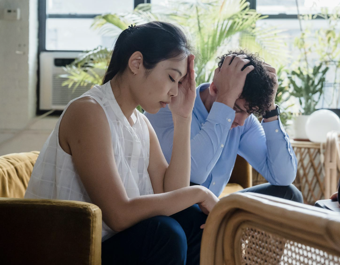 Two adults sitting together in a counseling setting, appearing concerned while receiving support during a session.