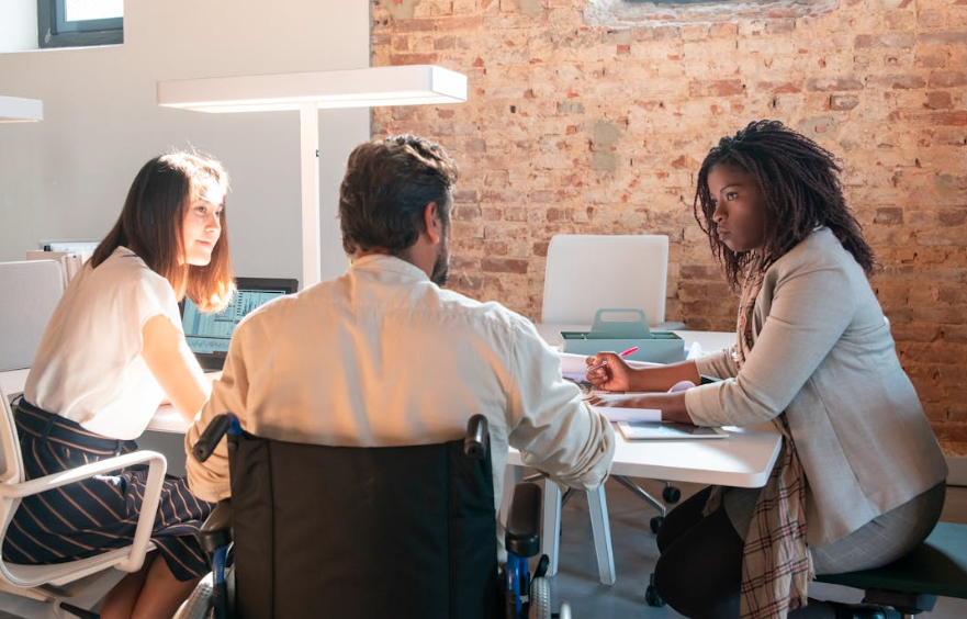 Diverse employees collaborating together during a workplace meeting, including a participant using a wheelchair.