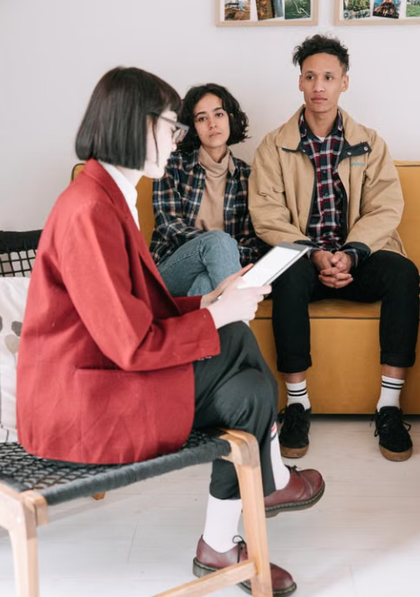 Two people speaking with a behavioral health professional during a counseling session.