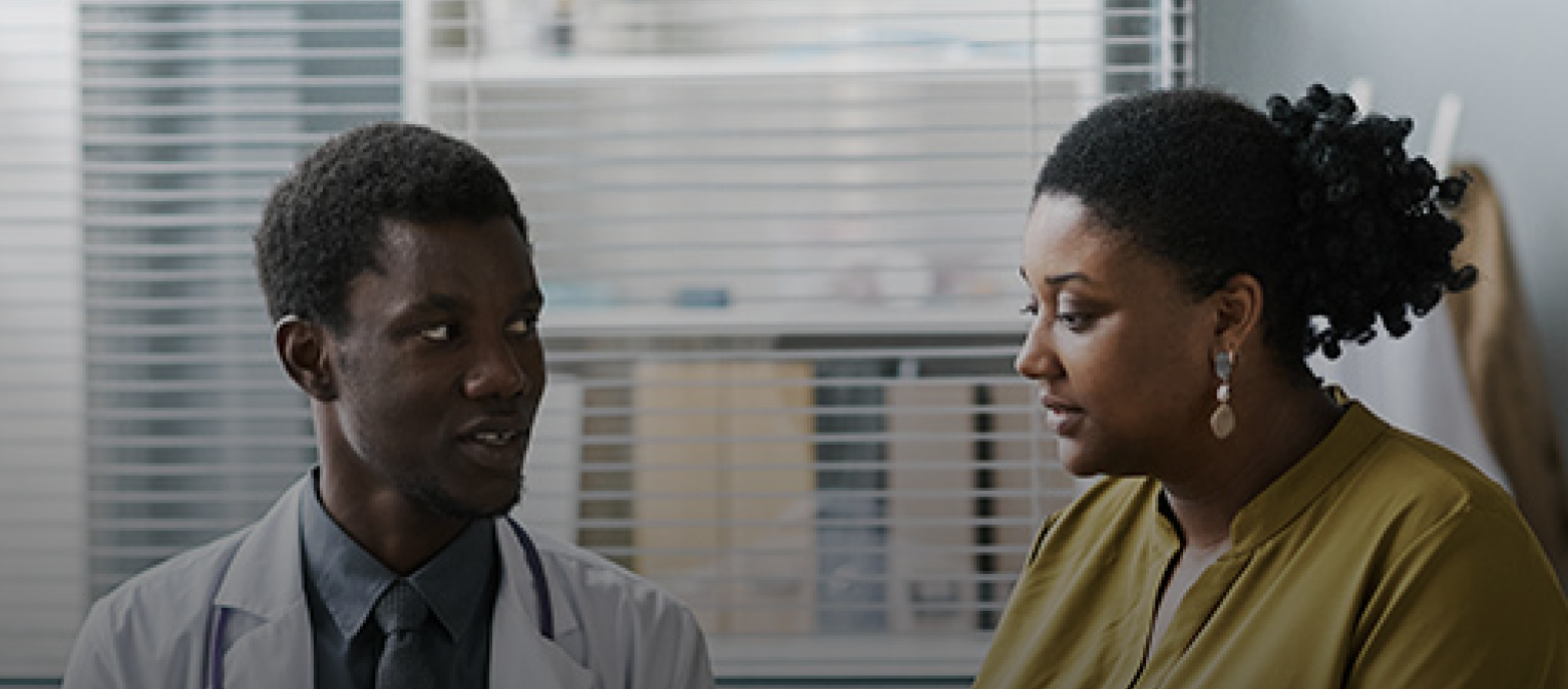 A health care professional and a woman having a conversation in a clinical office setting.