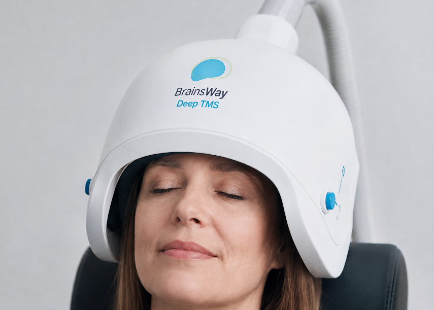 Patient receiving BrainsWay Deep TMS treatment while seated comfortably with the treatment helmet positioned over her head.