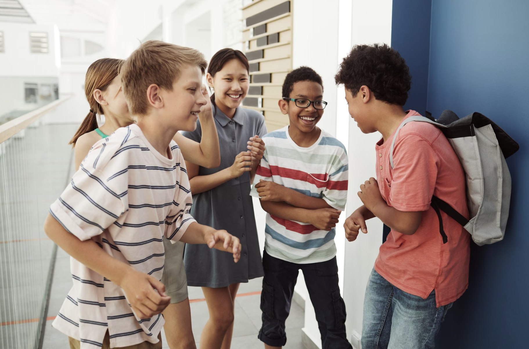 Diverse group of children and adolescents talking and smiling together at school.