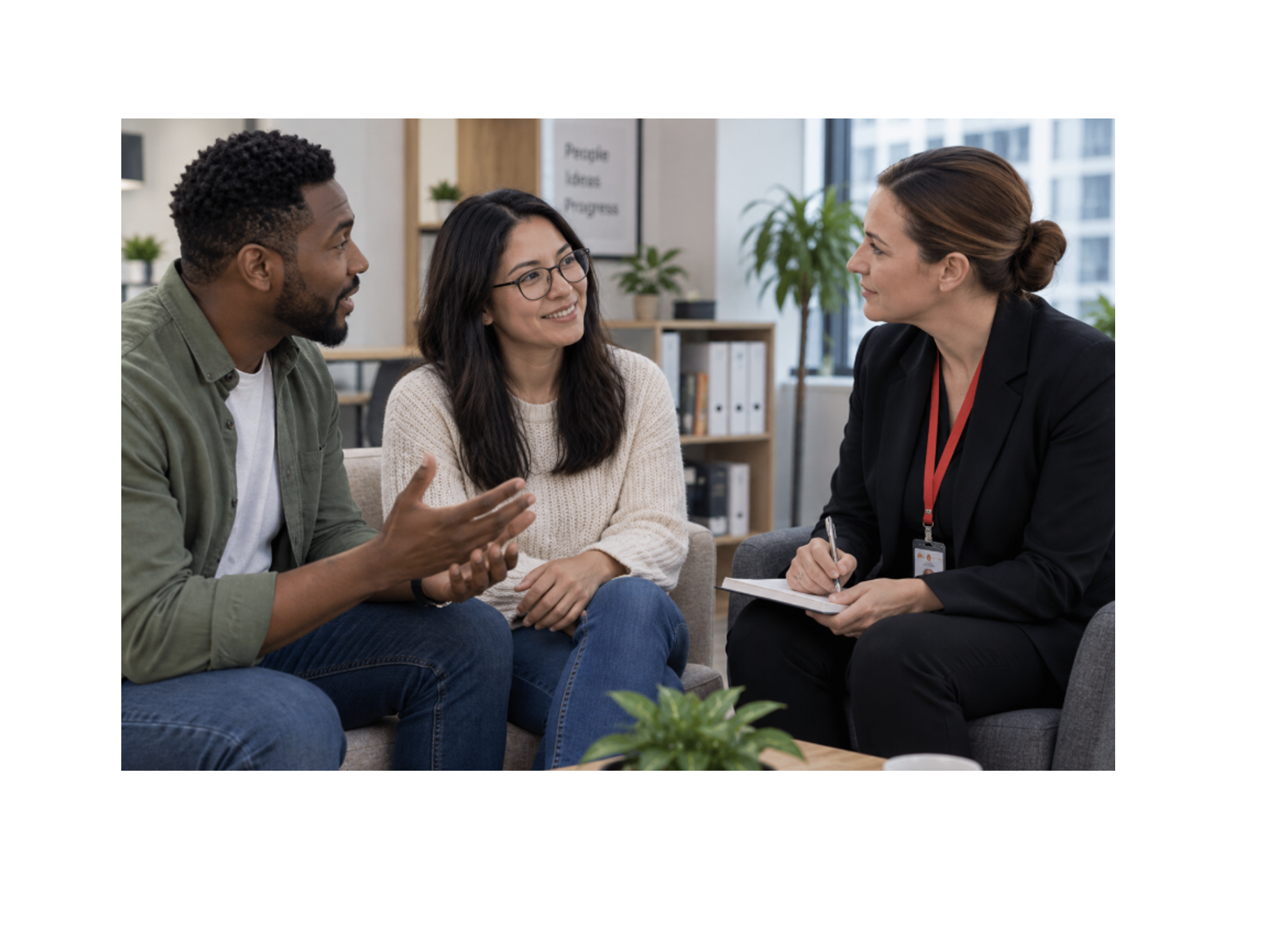 A behavioral health professional listens to a man and woman during a supportive conversation in an office.