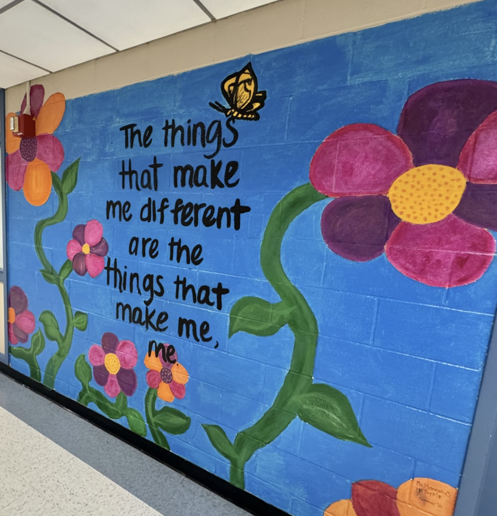 Colorful hallway mural with flowers, a butterfly, and a message celebrating individuality.