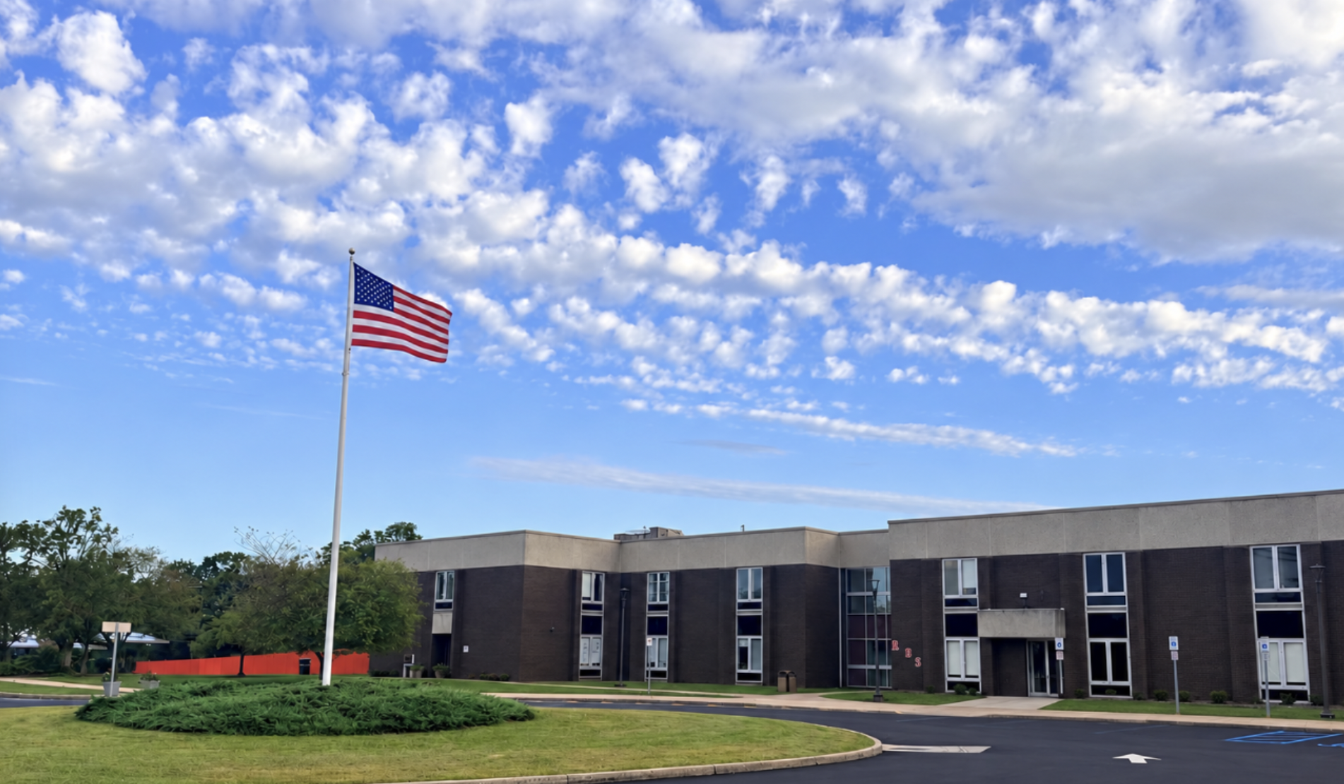 Exterior of a Rutgers University Behavioral Health Care facility with an American flag flying in front of the building.